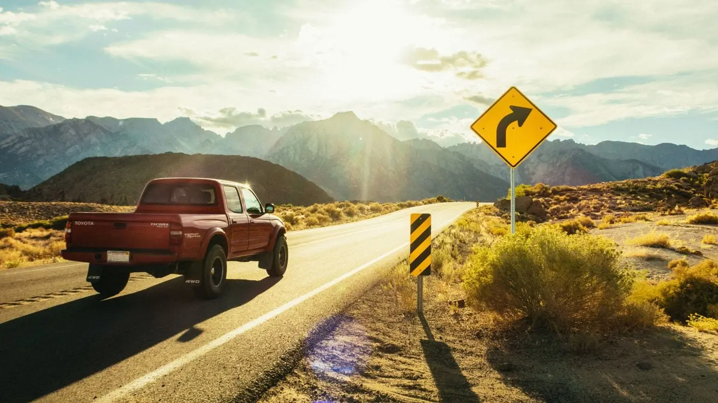 A pickup truck on an open road through the West Texas hills at golden hour
